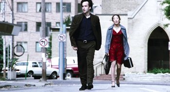 Movie still from “Last Night” (1998), directed by Don McKellar – A man and a woman walking down a street; Medium shot, Low angle