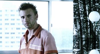 Movie still from “Last Night” (1998), directed by Don McKellar – A person wearing a polo shirt near a window; Close Up shot, Low angle