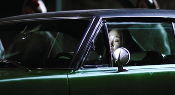 Movie still from “Last Night” (1998), directed by Don McKellar – A woman sitting in the driver's seat of a green car; Close Up shot, Low angle