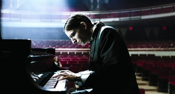 Movie still from “Last Night” (1998), directed by Don McKellar – A man in a black suit playing the piano; Medium shot, Low angle