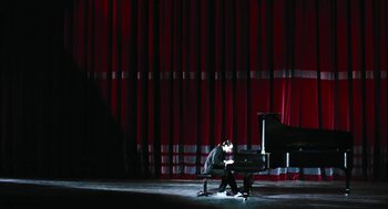 Movie still from “Last Night” (1998), directed by Don McKellar – A man sitting on a bench in front of a piano; Extreme Wide shot, Low angle