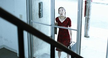 Movie still from “Last Night” (1998), directed by Don McKellar – A woman in a red dress holding a suitcase; Medium shot, High angle