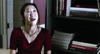 Movie still from “Last Night” (1998), directed by Don McKellar – A woman sitting in front of a book shelf crying; Close Up shot, High angle