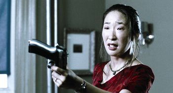 Movie still from “Last Night” (1998), directed by Don McKellar – A woman in a red dress is holding a gun; Close Up shot, Over the shoulder angle