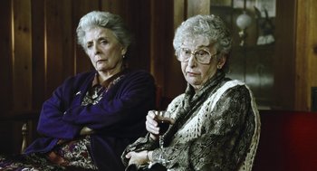 Movie still from “Last Night” (1998), directed by Don McKellar – Two older women sitting next to each other holding a glass of red wine; Medium shot, Low angle