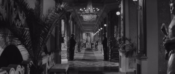 Movie still from “Last Year at Marienbad” (1961), directed by Alain Resnais – Two men are standing in an ornate hallway; Wide shot, Low angle