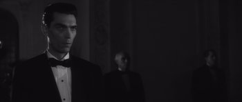 Movie still from “Last Year at Marienbad” (1961), directed by Alain Resnais – A man standing next to another man wearing a suit; Medium shot, Low angle