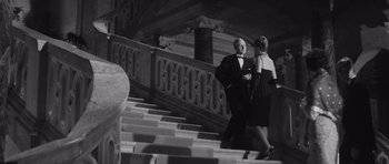 Movie still from “Last Year at Marienbad” (1961), directed by Alain Resnais – A man and a woman walking down a set of stairs; Wide shot, Low angle