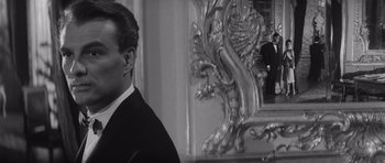 Movie still from “Last Year at Marienbad” (1961), directed by Alain Resnais – A black and white photo of a man looking at himself in a mirror; Close Up shot, Over the shoulder angle