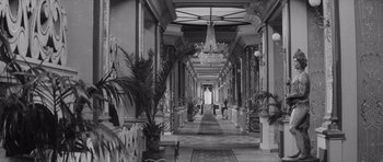 Movie still from “Last Year at Marienbad” (1961), directed by Alain Resnais – A black - and - white photo of a long hallway; Wide shot, High angle