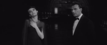 Movie still from “Last Year at Marienbad” (1961), directed by Alain Resnais – A man and a woman standing next to each other in front of a mirror; Medium shot, Low angle