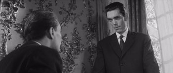 Movie still from “Last Year at Marienbad” (1961), directed by Alain Resnais – A black and white photo of a man in a suit looking at himself in the mirror; Medium shot, Over the shoulder angle