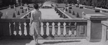 Movie still from “Last Year at Marienbad” (1961), directed by Alain Resnais – A black and white photo of a woman looking over a fence; Medium shot, High angle