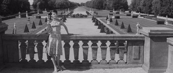 Movie still from “Last Year at Marienbad” (1961), directed by Alain Resnais – A woman standing on a balcony in a park; Wide shot, Low angle