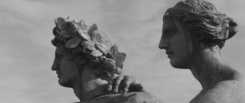 Movie still from “Last Year at Marienbad” (1961), directed by Alain Resnais – A black and white photo of a statue of a man and a woman; Close Up shot, Low angle