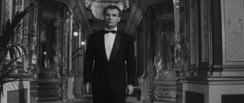 Movie still from “Last Year at Marienbad” (1961), directed by Alain Resnais – A man in a tuxedo standing in a hallway; Medium shot, Low angle