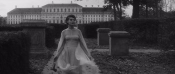 Movie still from “Last Year at Marienbad” (1961), directed by Alain Resnais – A black and white photo of a woman walking in a park; Wide shot, Low angle