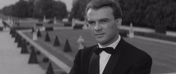 Movie still from “Last Year at Marienbad” (1961), directed by Alain Resnais – Black and white photograph of a man in a tuxedo; Close Up shot, Over the shoulder angle
