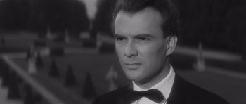 Movie still from “Last Year at Marienbad” (1961), directed by Alain Resnais – Black and white photograph of a man wearing a tuxedo; Close Up shot, Over the shoulder angle