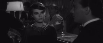 Movie still from “Last Year at Marienbad” (1961), directed by Alain Resnais – A black and white photo of a woman in a bar; Close Up shot, Over the shoulder angle