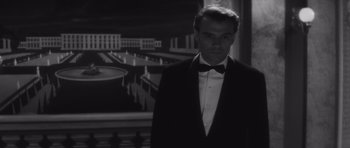 Movie still from “Last Year at Marienbad” (1961), directed by Alain Resnais – A black and white photo of a man in a tuxedo; Medium shot, Low angle