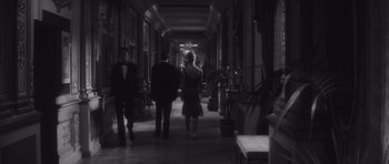 Movie still from “Last Year at Marienbad” (1961), directed by Alain Resnais – A black - and - white photo of people walking down a hall way; Wide shot, Low angle