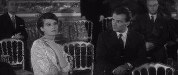 Movie still from “Last Year at Marienbad” (1961), directed by Alain Resnais – A man and a woman sitting next to each other; Medium shot, Over the shoulder angle