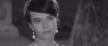 Movie still from “Last Year at Marienbad” (1961), directed by Alain Resnais – A black and white photo of a woman in a black dress; Close Up shot, Over the shoulder angle