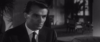 Movie still from “Last Year at Marienbad” (1961), directed by Alain Resnais – Black and white photograph of a man wearing a suit and tie; Close Up shot, Over the shoulder angle