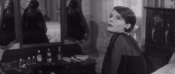 Movie still from “Last Year at Marienbad” (1961), directed by Alain Resnais – A woman standing in front of a mirror in a room; Medium shot, Over the shoulder angle