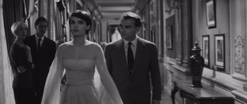 Movie still from “Last Year at Marienbad” (1961), directed by Alain Resnais – A man and a woman walking down a hall way; Medium shot, Low angle
