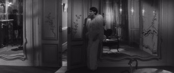 Movie still from “Last Year at Marienbad” (1961), directed by Alain Resnais – A black and white photo of a woman in a fur coat; Medium shot, High angle