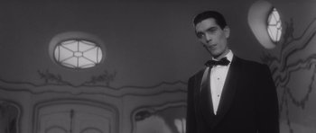 Movie still from “Last Year at Marienbad” (1961), directed by Alain Resnais – A man in a tuxedo standing in front of a mirror; Medium shot, Low angle