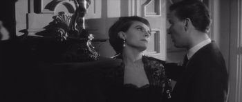 Movie still from “Last Year at Marienbad” (1961), directed by Alain Resnais – A black and white photo of a woman looking up; Close Up shot, Over the shoulder angle