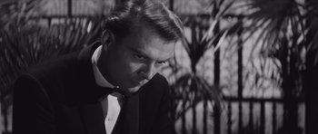 Movie still from “Last Year at Marienbad” (1961), directed by Alain Resnais – A black and white photo of a man in a suit; Close Up shot, Over the shoulder angle