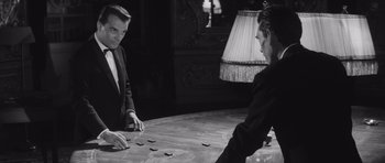 Movie still from “Last Year at Marienbad” (1961), directed by Alain Resnais – Two men are playing a game on a table; Medium shot, High angle