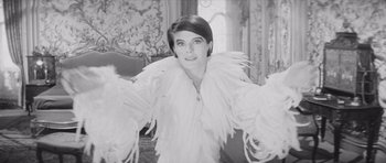 Movie still from “Last Year at Marienbad” (1961), directed by Alain Resnais – A black - and - white photo of a woman wearing a white feather jacket; Medium shot, Low angle