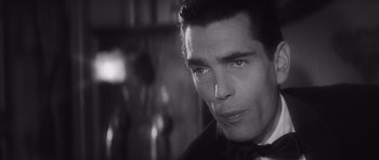 Movie still from “Last Year at Marienbad” (1961), directed by Alain Resnais – Black and white photograph of a man in a tuxedo; Close Up shot, Over the shoulder angle