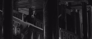 Movie still from “Last Year at Marienbad” (1961), directed by Alain Resnais – A black and white photo of a man in a suit and tie; Wide shot, Low angle