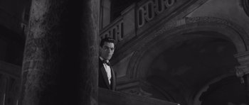 Movie still from “Last Year at Marienbad” (1961), directed by Alain Resnais – A black and white photo of a man in a tuxedo; Medium shot, Low angle