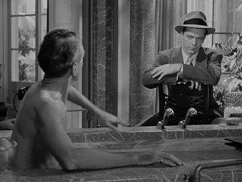 Movie still from “Laura” (1944), directed by Rouben Mamoulian – A black and white photo of a man in a hat looking in the mirror; Medium shot, Over the shoulder angle