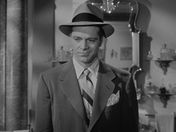 Movie still from “Laura” (1944), directed by Rouben Mamoulian – A black and white photo of a man wearing a suit and hat; Medium shot, Low angle