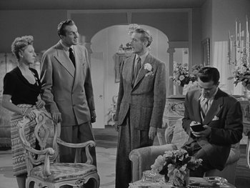 Movie still from “Laura” (1944), directed by Rouben Mamoulian – A group of men and women standing in a living room; Wide shot, Over the shoulder angle