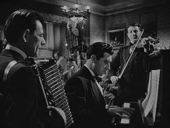 Movie still from “Laura” (1944), directed by Rouben Mamoulian – A group of men playing musical instruments in a room; Medium shot, Low angle