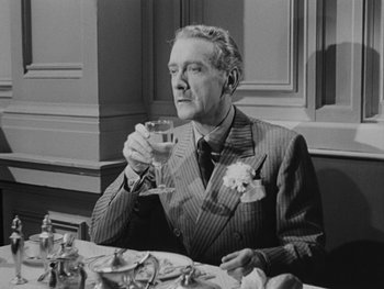 Movie still from “Laura” (1944), directed by Rouben Mamoulian – An older man sitting at a dinner table drinking a glass of wine; Medium shot, Low angle