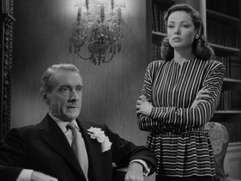 Movie still from “Laura” (1944), directed by Rouben Mamoulian – An older man and a younger woman in front of a chandelier; Medium shot, Low angle