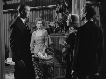 Movie still from “Laura” (1944), directed by Rouben Mamoulian – A group of people standing next to each other in a room; Medium shot, Over the shoulder angle