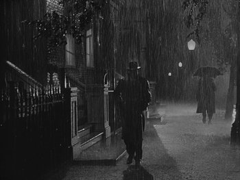 Movie still from “Laura” (1944), directed by Rouben Mamoulian – A man walking down a street in the rain; Wide shot, High angle