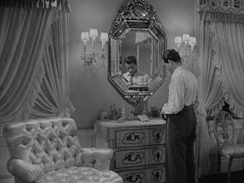 Movie still from “Laura” (1944), directed by Rouben Mamoulian – A man standing in front of a mirror in a room; Wide shot, High angle