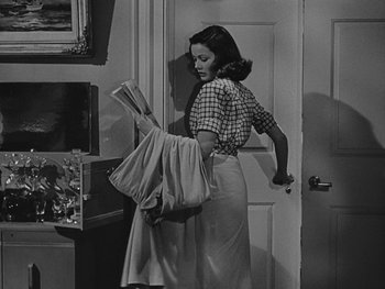 Movie still from “Laura” (1944), directed by Rouben Mamoulian – A black and white photo of a woman holding a laundry basket; Medium shot, Low angle
